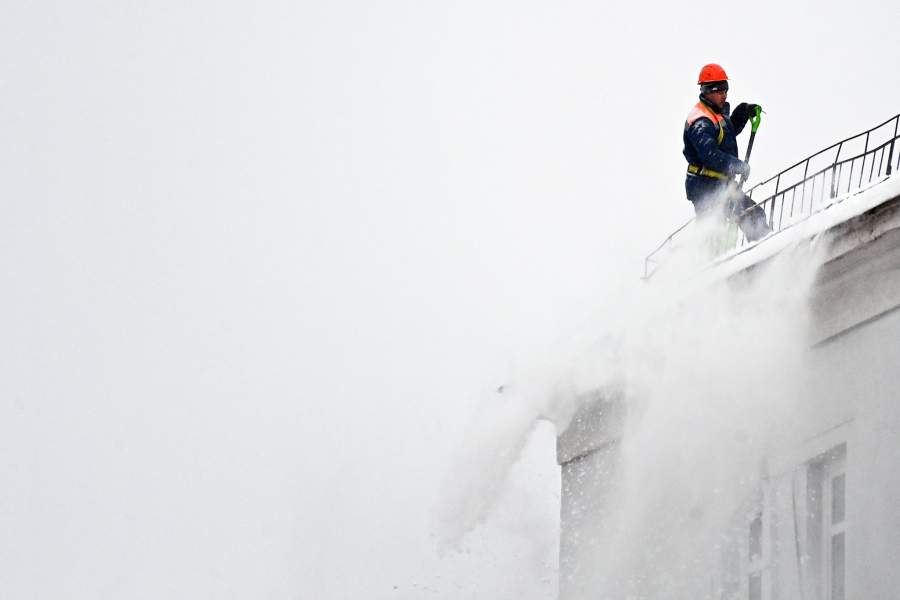 Сотрудник коммунальных служб во время чистки крыши одного из многоквартирных домов после сильного снегопада в Москве