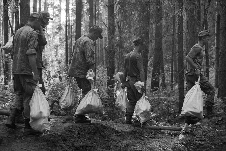 Поисковики несут мешки с останками найденных без вести пропавших солдат через густой лес. Останки каждого солдата складываются в отдельный мешок вместе с его личными вещами для перезахоронения, р-н Ржева 