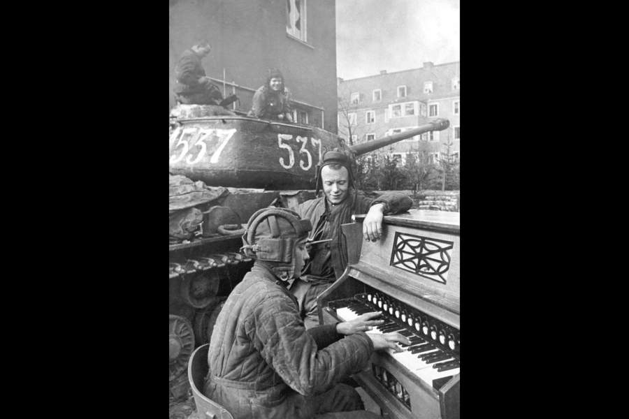 Танковый экипаж гвардии лейтенанта Б.Дегтярева на отдыхе. Башенный стрелок Б.Калякин играет классическую музыку своему экипажу, рядом с ним стоит механик-водитель А.Козейкин. 1-й Украинский фронт, 87 гвардейский тяжелый танковый полк, Бреслау. 27 апреля 1945 год. 