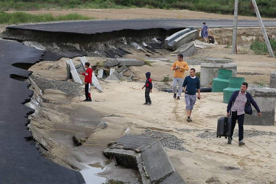 Люди пытаются пешком добраться до аэропорта по размытой ливнями дороге А290 в районе села Цибанобалка в Краснодарском крае.