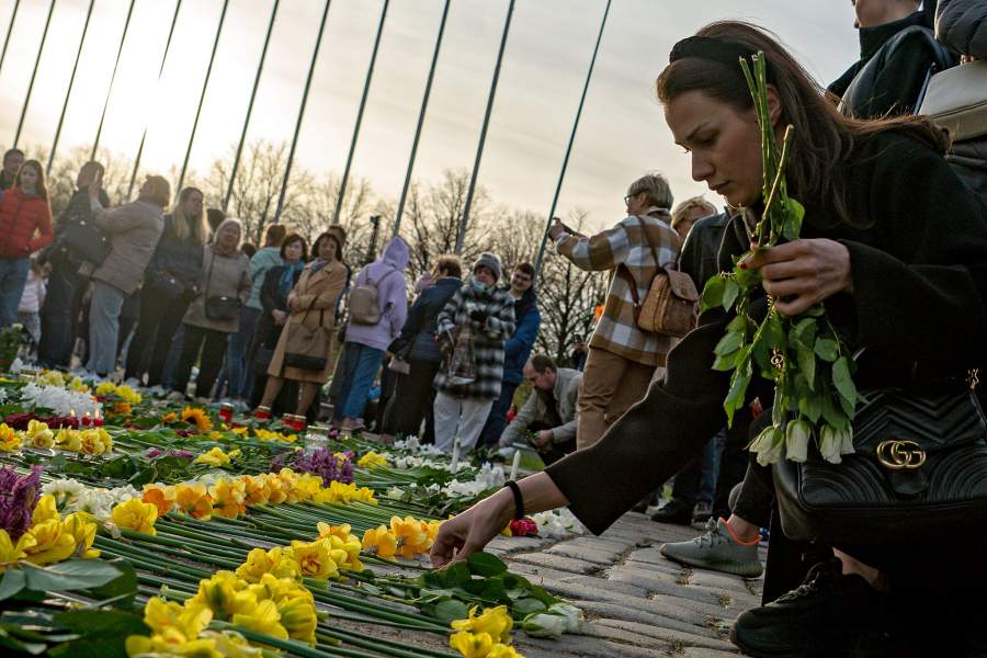 Женщина возлагает цветы у мемориального комплекса "Памятник воинам Советской Армии - освободителям Советской Латвии и Риги от немецко-фашистских захватчиков" в Риге.