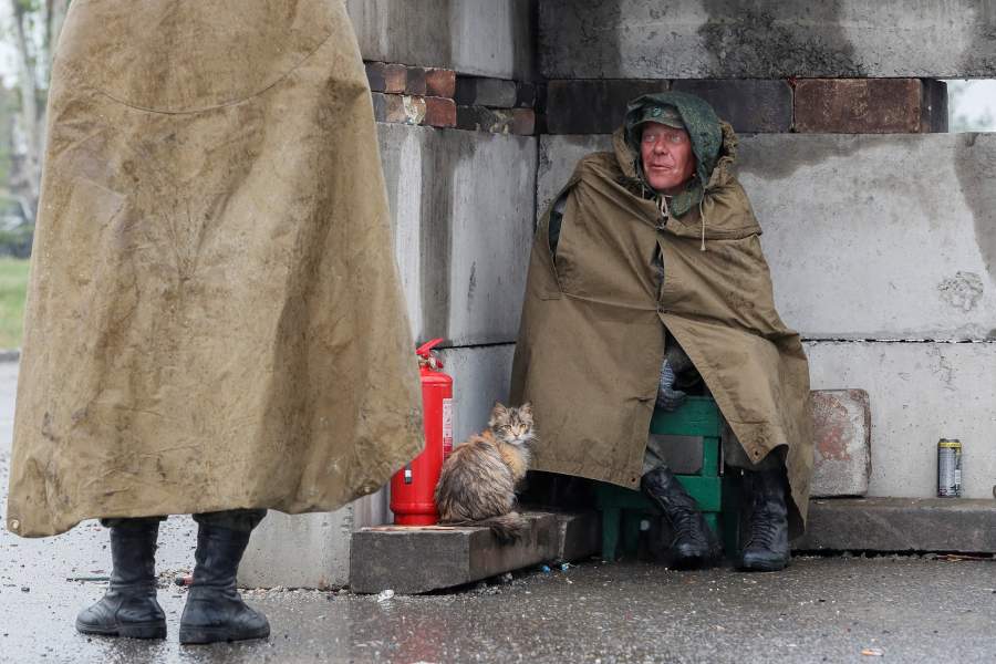 A service member of pro-Russian troops sits next to a cat before the expected departure of Ukrainian soldiers, who surrendered at the besieged Azovstal steel mill, in the course of Ukraine-Russia conflict in Mariupol