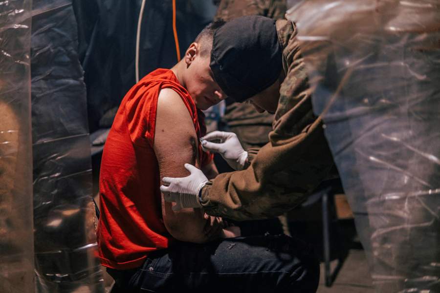 An injured Ukrainian service member receives medical assistance in a field hospital inside a bunker of the Azovstal Iron and Steel Works in Mariupol