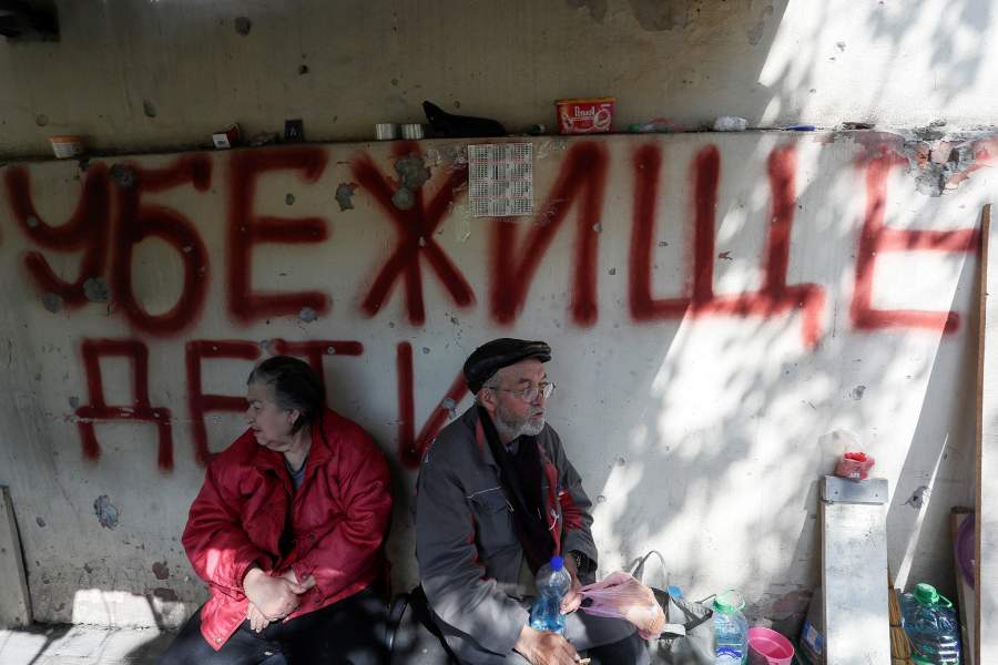 Local residents sit outside a block of flats heavily damaged during Ukraine-Russia conflict in the southern port city of Mariupol