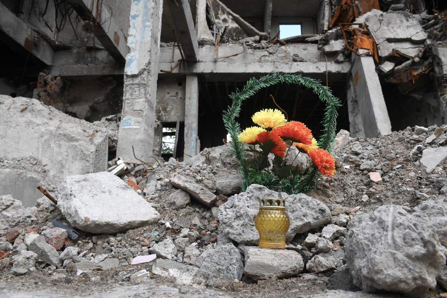 Венок и лампада на месте разрушенного здания в Мариуполе