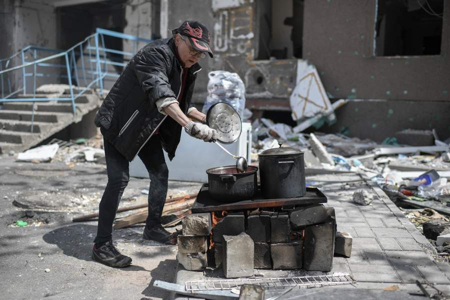 Женщина готовит еду на одной из улиц в Мариуполе