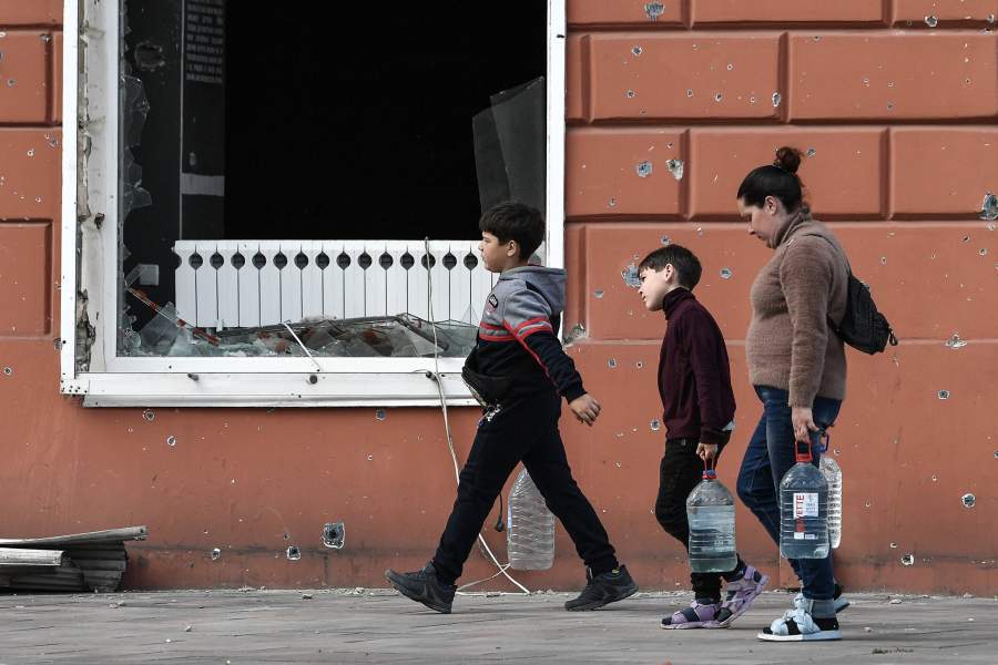 Местные жители несут бутылки с водой на одной из улиц в Мариуполе