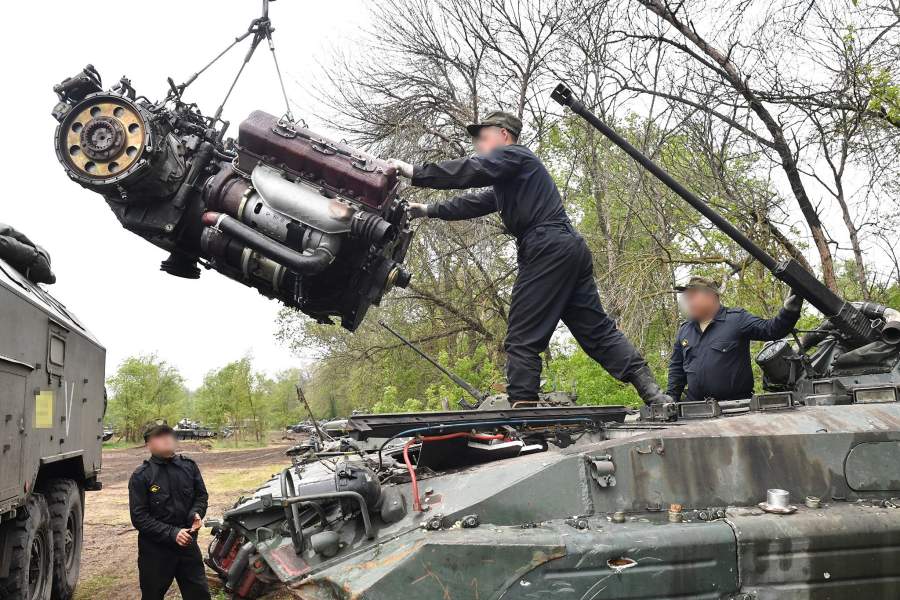 Военнослужащие ремонтно-восстановительного полка Вооруженных сил РФ устанавливают двигатель на боевую машину пехоты БМП-2 в полевых условиях в зоне специальной военной операции на Украине
