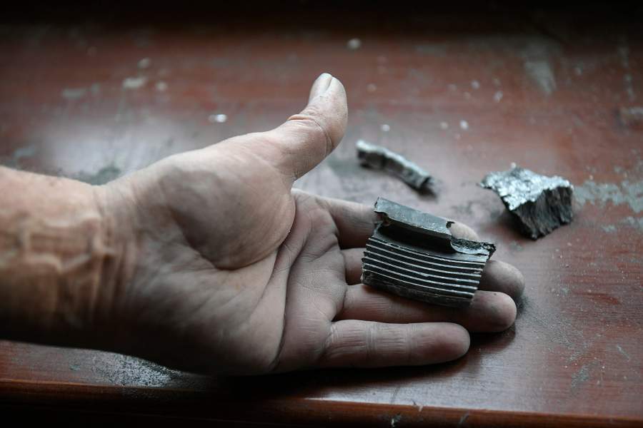 Мужчина держит в руках осколки снаряда, выпущенного ВСУ по Куйбышевскому району Донецка