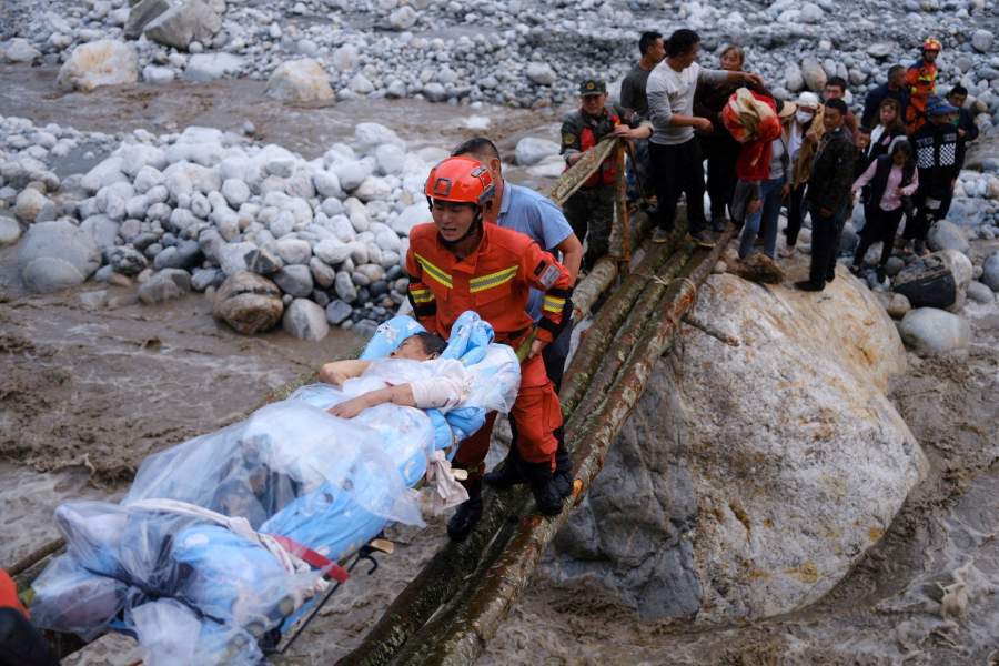 Спасатели эвакуируют пострадавшую женщину после разрушительного землетрясения в Сычуани, Китай