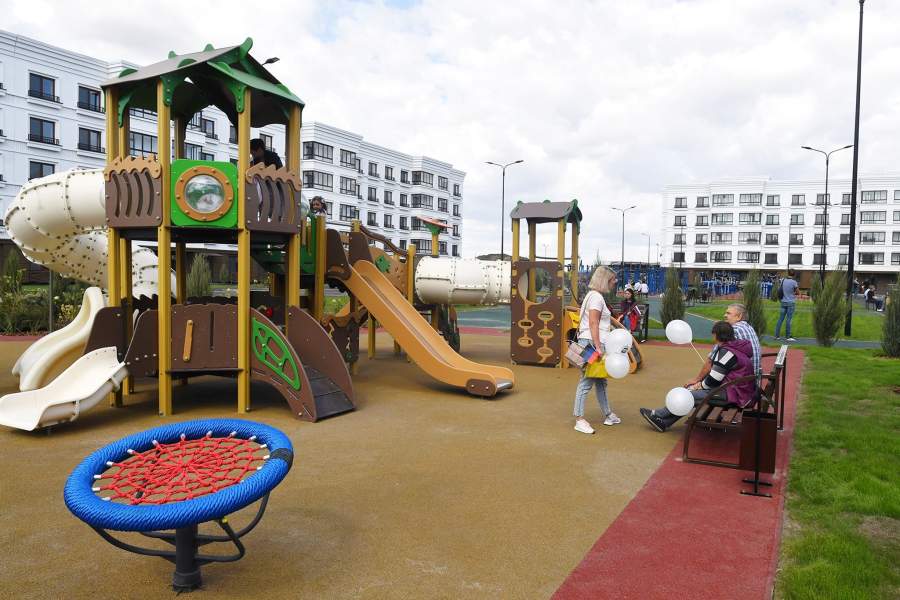 Жители на детской площадке во дворе жилого дома, построенного представителями военно-строительного комплекса Министерства обороны России в Мариуполе