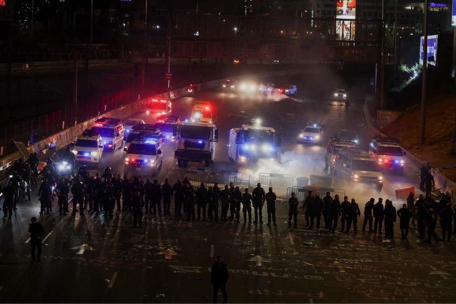 Members of security forces stand guard as people attend a demonstration after Israeli Prime Minister Benjamin Netanyahu dismissed the defense minister and his nationalist coalition government presses on with its judicial overhaul, in Tel Aviv,