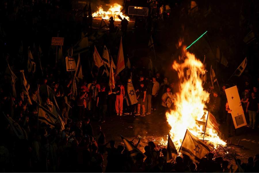 Fire burns as people attend a demonstration after Israeli Prime Minister Benjamin Netanyahu dismissed the defense minister and his nationalist coalition government presses on with its judicial overhaul, in Tel Aviv