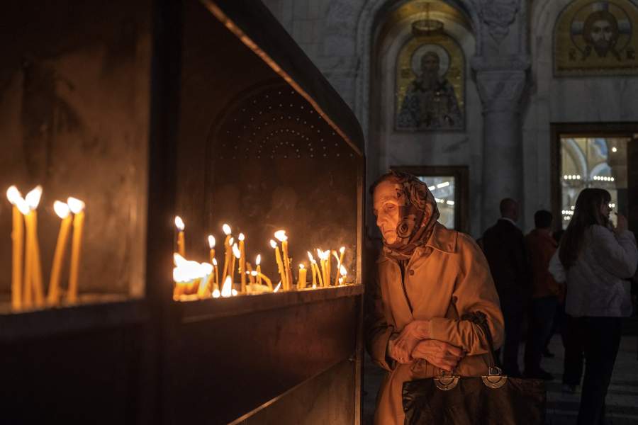 A woman looks at the burning candles during the midnight Orthodox Easter holy liturgy at St. Sava temple in Belgrade, Serbia