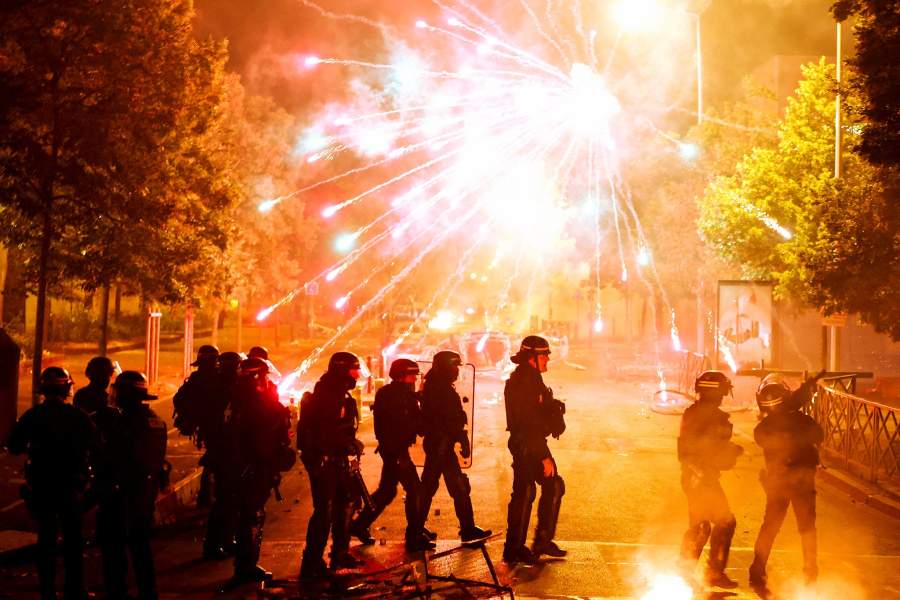 French police stand in position as fireworks go off during clashes with youth, after the death of Nahel, a 17-year-old teenager killed by a French police officer during a traffic stop, in Nanterre, Paris suburb, France, June 30, 2023.
