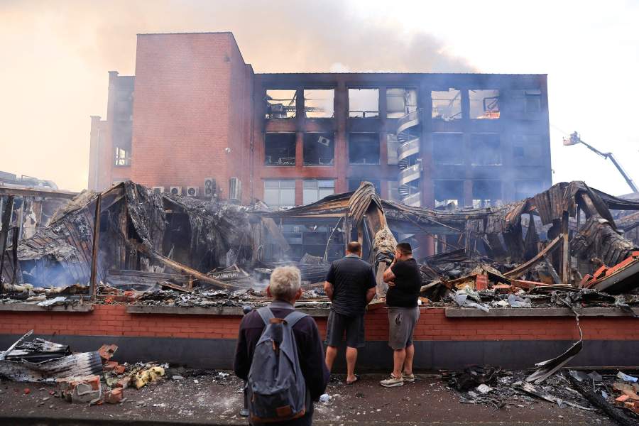 People look at a building of the Tessi group, burnt during night clashes between protesters and police, following the death of Nahel, a 17-year-old teenager killed by a French police officer in Nanterre during a traffic stop, at the Alma district in Roubaix, northern France, June 30, 2023.