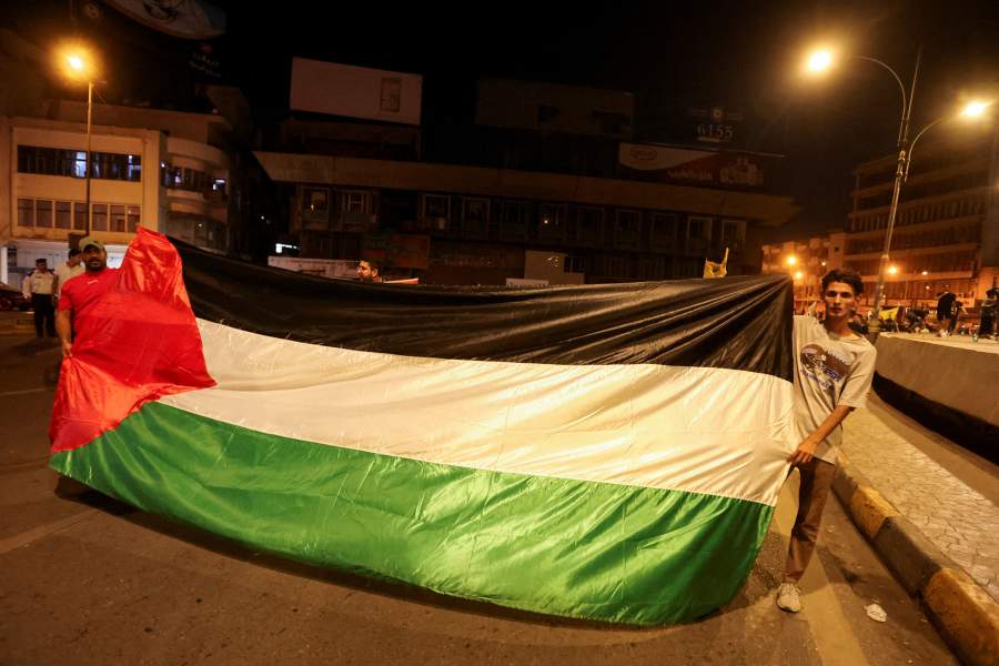 Иракцы держат палестинский флаг, принимая участие в акции протеста после того, как сотни палестинцев погибли в результате взрыва в больнице «Аль-Ахли» в секторе Газа