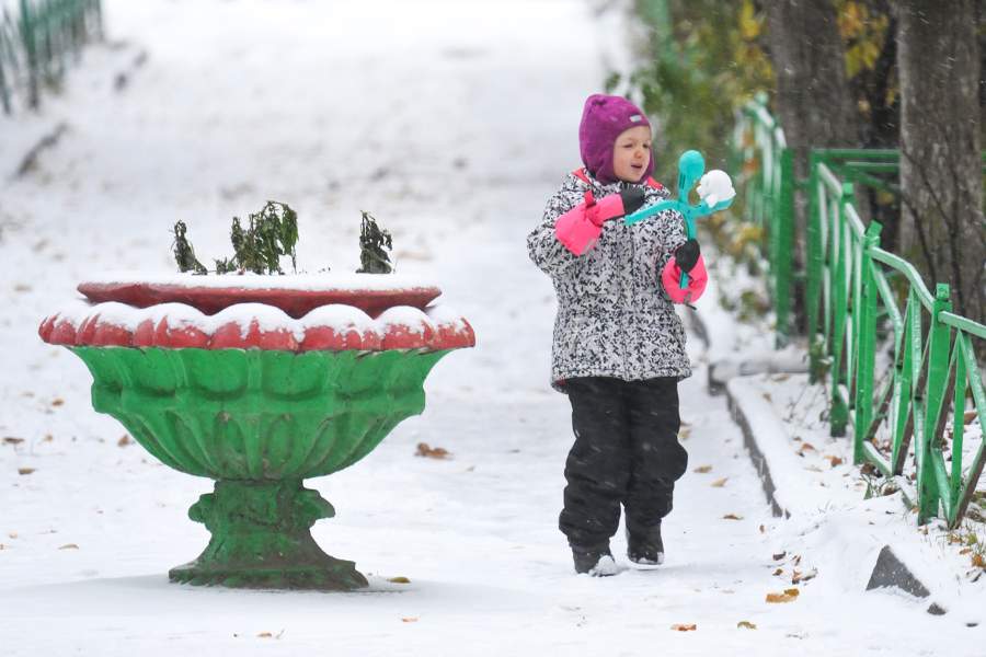 Девочка лепит снежок во время снегопада на одной из улиц Москвы. В столичном регионе выпал первый снег. До конца дня 27 октября МЧС обещает метель, гололедицу и порывы ветра до 15 м/с