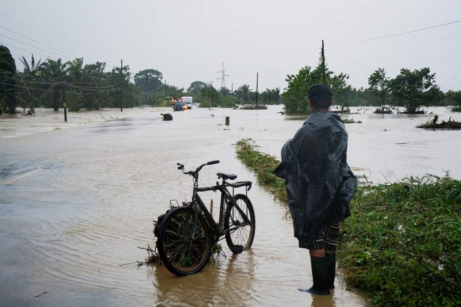 Мужчина стоит рядом со своим велосипедом на затопленной дороге после того, как река Аризона вышла из берегов из-за сильного дождя, вызванного тропическим штормом Сара, в Теле, Гондурас, 15 ноября 2024 года