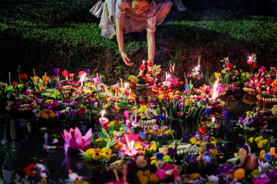 Женщина кладет кратонг, плавучую корзину из листьев и цветов, в лагуну парка во время фестиваля «Лой Кратонг», который проводится в качестве символического извинения и выражения благодарности богине реки за воду, в Бангкоке, Таиланд, ноябрь. 15, 2024