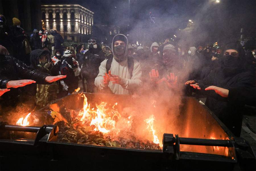 Грузия. Тбилиси. Протестующие греют руки от огня, разведенного в мусорном баке у здания парламента на проспекте Руставели. Демонстрация проходит на фоне решения властей отказаться от переговоров о вступлении в Евросоюз