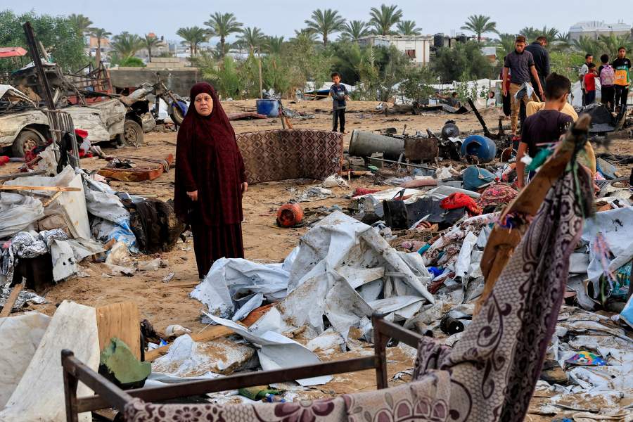 Палестинцы осматривают ущерб на месте израильского удара по палаточному лагерю, в котором укрывались перемещенные лица, в Хан-Юнисе, на юге сектора Газа.