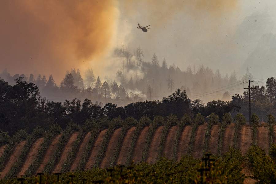 Вертолет летит над дымом от пожара возле виноградника в округе Напа, Калифорния, США