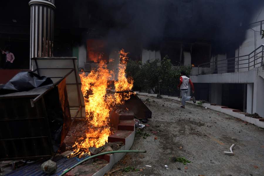 Демонстрант пробегает мимо пламени возле офиса партии Непальский конгресс во время протеста против убийства 19 человек в понедельник после антикоррупционных протестов, спровоцированных запретом на социальные сети, который позже был снят во время комендантского часа в Катманду, Непал.