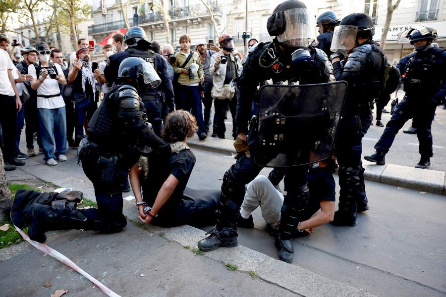 Французская полиция по борьбе с беспорядками задерживает протестующих во время столкновений на демонстрации в Париже в рамках общенациональной акции протеста против правительства