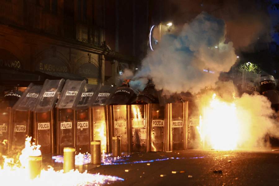 Сотрудник полиции пытается потушить пожар в день протеста студентов педагогического колледжа имени Рауля Исидро Бургоса в Айоцинапе, приуроченного к 11-й годовщине исчезновения 43 студентов, в Мехико, Мексика