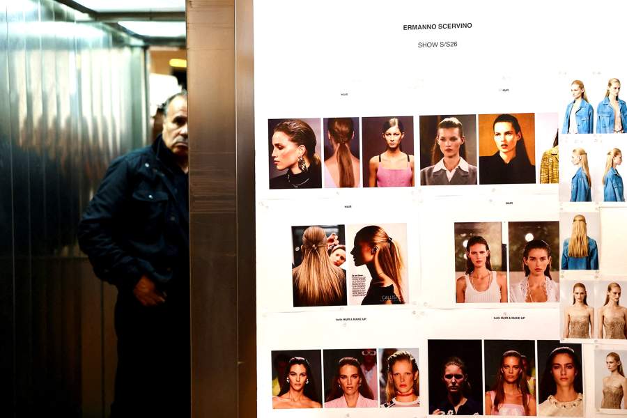 A person uses an elevator near the pictures of the models at Ermanno Scervino spring/summer 2026 collection show during Fashion Week in Milan, Italy, September 27, 2025
