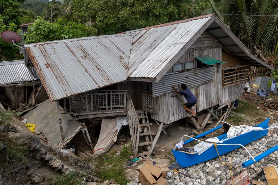 Relatives of Manuel Mandabon, the 87-year-old owner of the damaged house, cover the windows of his residence following the 7.4 magnitude quake in Manay, Davao Oriental, Philippines, October 11, 2025