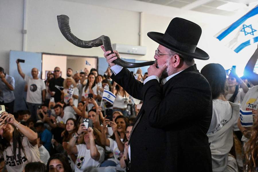 A man blows a shofar as relatives and friends of Israeli hostage Alon Ohel, held in Gaza since the deadly October 7, 2023 attack by Hamas, react as they watch broadcasts related to his release as part of a hostages-prisoners swap and a ceasefire deal in Gaza between Hamas and Israel, in Lavon, Israel October 13, 2025