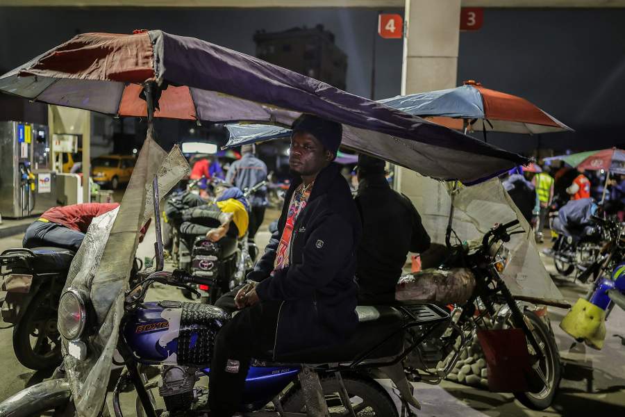 Zakiyaou Mohamed, 33, a motorcycle taxi rider who cannot afford to pay rent, stands on top of his motorcycle before sleeping on top of it at a fuel station in Douala, Cameroon, October 4, 2025. Though sometimes demonized by government officials who blame them for petty crime and disorder, "benskin" drivers say their plight encapsulates a bigger, more structural problem: lack of opportunity under President Paul Biya, who has ruled the Central African nation for more than four decades.