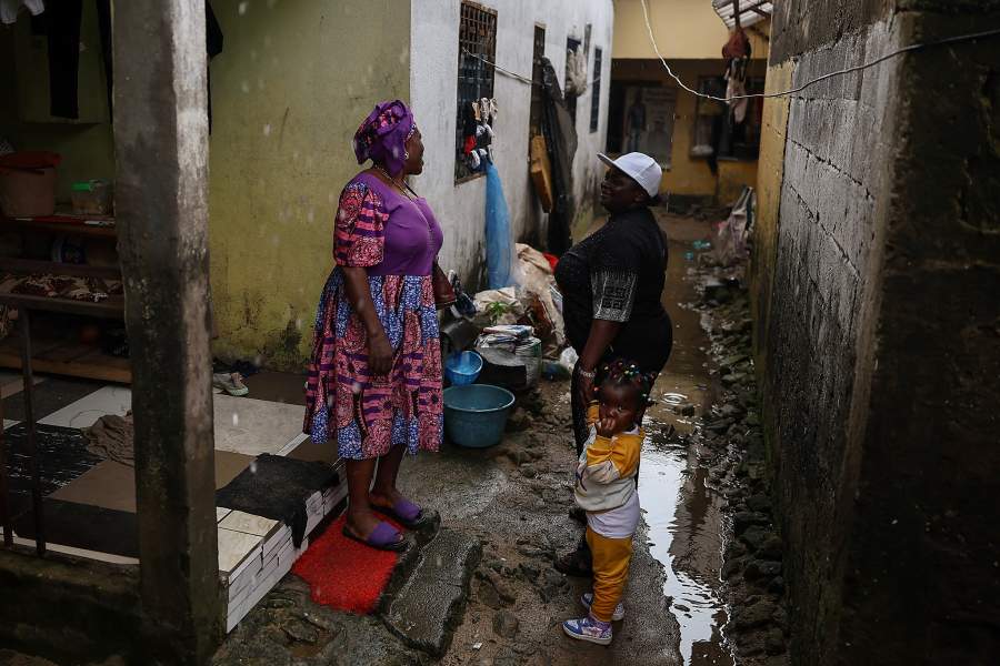 Carine Alphonsine Kegne, 39, a single mother of two and motorcycle taxi rider who abandoned her dream of becoming a professional football referee, holds her niece's hands as she talks to a neighbor in Douala, Cameroon, October 5, 2025. One day, a friend lent Kegne his motorcycle, and someone mistook her for a "benskin" driver, 