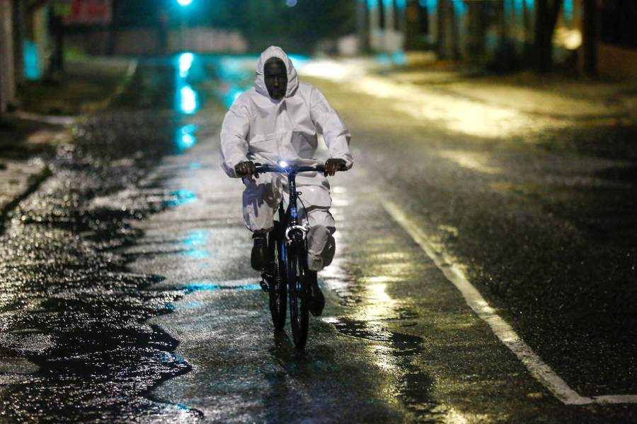 A man wearing a protective suit cycles on a street, as Hurricane Melissa approaches, in Kingston, Jamaica