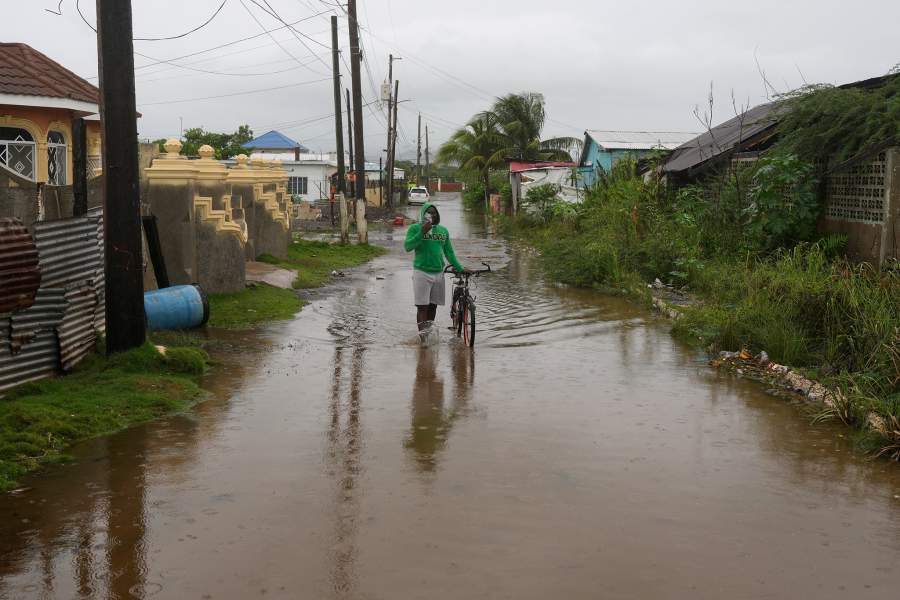 A man wades through a flooded street ahead of the forecasted arrival of Hurricane Melissa in Old Harbour, Jamaica