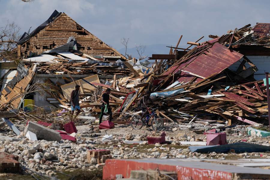 Residents make their way past piles of debris in the aftermath of Hurricane Melissa in Black River, Jamaica, Thursday, Oct. 30, 2025