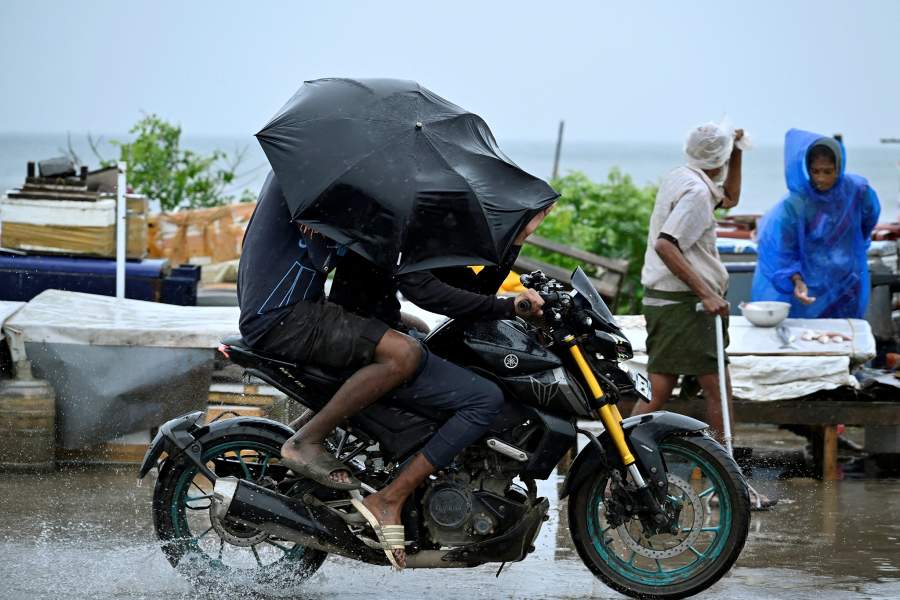Motorcyclists cover themselves with an umbrella as it drizzles, before Cyclone Montha makes landfall, in Chennai, India, October 28, 2025