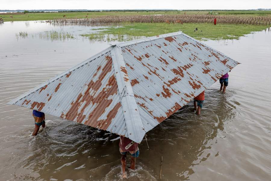 Relatives and neighbours help move the house of Kosim Uddin, 50, to another island in the Brahmaputra River, as the current one is on the verge of being destroyed by erosion, in Kurigram, Bangladesh, June 20, 2024. REUTERS/Mohammad Ponir Hossain