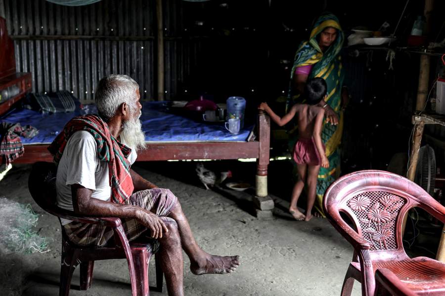 Kosim Uddin, 50, sits on a chair while his wife and daughter interact in his home, located on an island in the Brahmaputra River where he recently relocated due to erosion, in Kurigram, Bangladesh, October 29, 2025. REUTERS/Mohammad Ponir Hossain