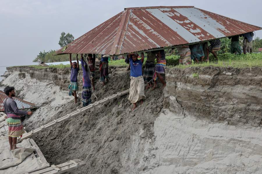 People carry the roof of the house belonging to Nurun Nabi, 30, to load onto a boat, after he was forced to relocate to another island due to erosion caused by the Brahmaputra River, in Kurigram, Bangladesh, October 29, 2025. REUTERS/Mohammad Ponir Hossain