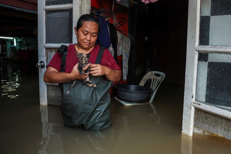A woman holds her kitten as she poses for a picture at her home in the Tha-It community, which is partially submerged on the banks of the Chao Phraya River after increased discharge from the Chao Phraya Dam, in Nonthaburi province on the outskirts of Bangkok, Thailand, November 14, 2025. REUTERS/Chalinee Thirasupa