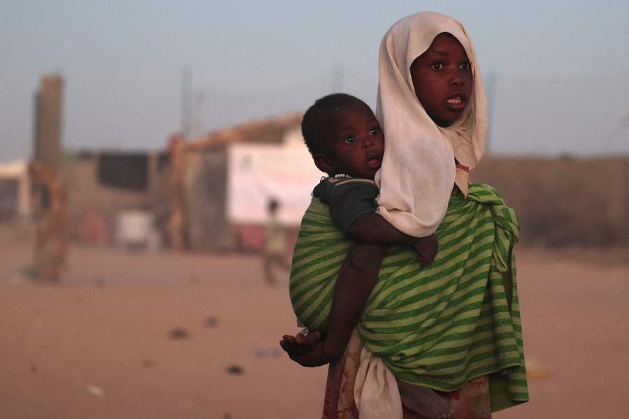 A Sudanese refugee girl from Al-Fashir carries her brother at the Tine transit refugee camp, amid the conflict between the paramilitary Rapid Support Forces (RSF) and the Sudanese army, in eastern Chad, November 21, 2025. REUTERS/Amr Abdallah Dalsh TPX IMAGES OF THE DAY