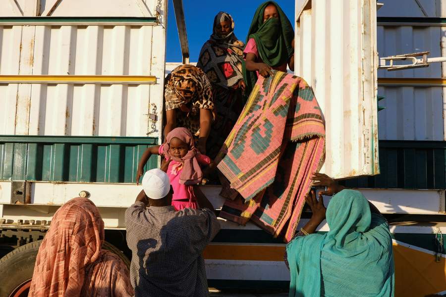 A displaced woman from al-Fashir hands a child to a volunteer to help them get down from a truck, at a displacement camp in Al-Dabba, Sudan, November 19, 2025. REUTERS/El Tayeb Siddig