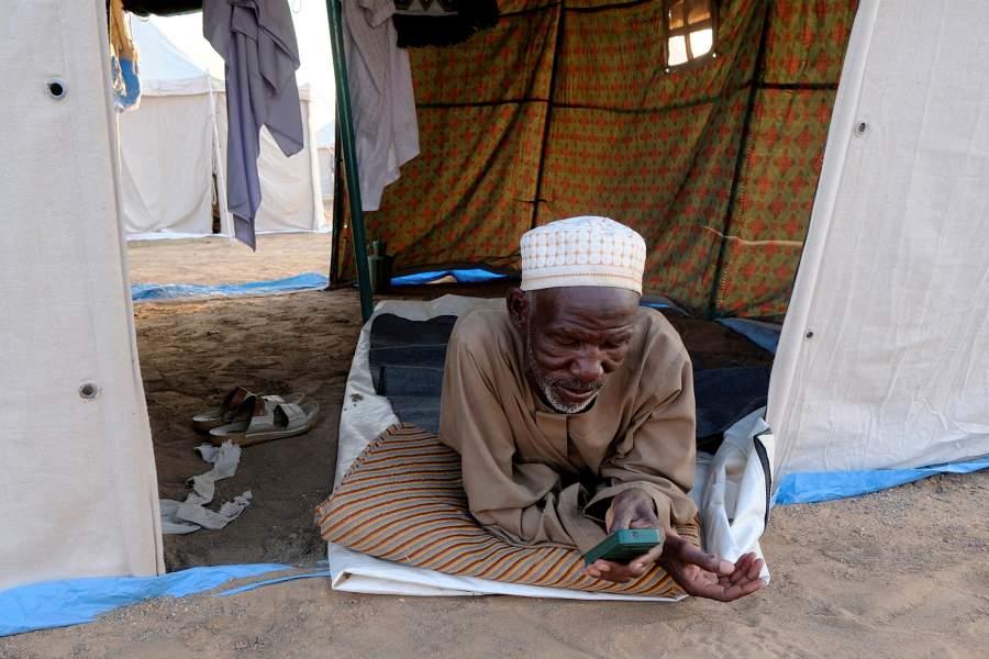 A displaced person uses a mobile phone while lying down in his tent at a displacement camp in Al-Dabbah, Sudan, November 12, 2025. REUTERS/El Tayeb Siddig