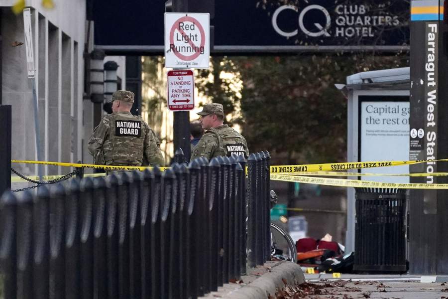 National Guard members stand in a cordoned-off area with evidence markers palced on the ground, after two National Guard members were shot near the White House in Washington