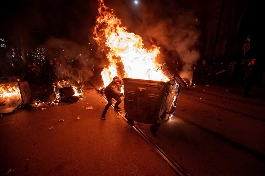 A protester pushes a burning garbage bin during scuffles with police at a demonstration organised by Bulgaria's opposition PP-DB coalition against the proposed financial framework of the country's budget, Sofia, Bulgaria