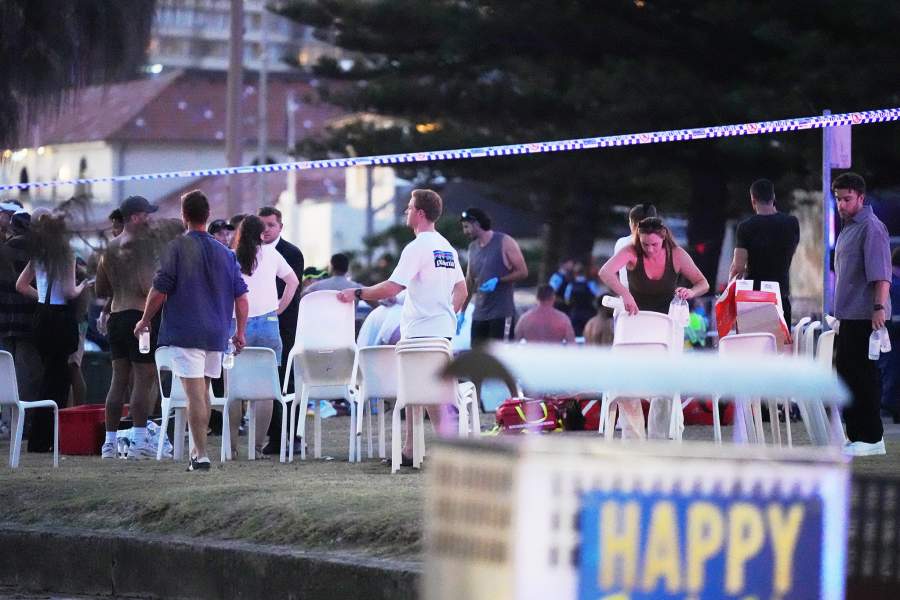People and emergency workers gather at location where a holiday event was taking place and then a reported shooting at Bondi Beach in Sydney, Sunday, Dec. 14, 2025.