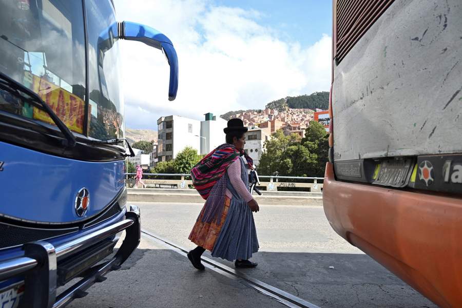 A woman walks past buses blocking the roads as drivers stage a nationwide strike and roadblocks in protest against the government’s announced removal of fuel subsidies, in La Paz, Bolivia, December 19, 2025